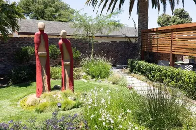 two statues of people standing in a garden at Garten Wohnung mit Pool, 2 Schlafzimmer in Cape Town