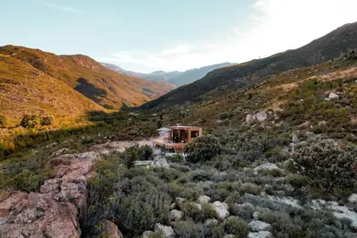a house in the middle of a valley with mountains at Luxury Solace Cabin - River Cabin in Rawsonville