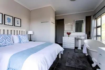 a bedroom with a bed and a tub and a sink at Vue La Mer in Hermanus