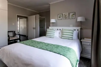 a bedroom with a large white bed with green pillows at Vue La Mer in Hermanus