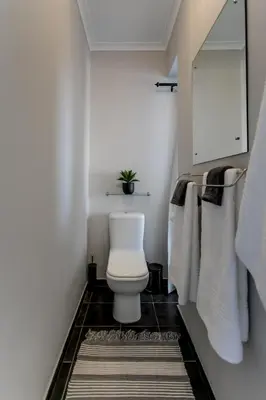 a bathroom with a toilet and towels and a rug at Vue La Mer in Hermanus