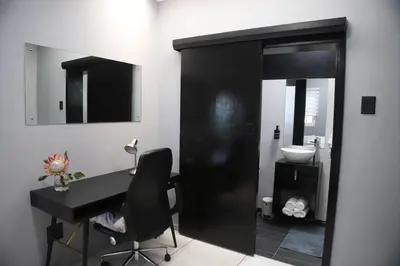 a bathroom with a black desk and a sink at Trendy Cottage Hideaway in Cape Town