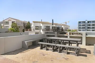 a rooftop with benches and tables on a building at Sea Spray AG04 in Bloubergstrand