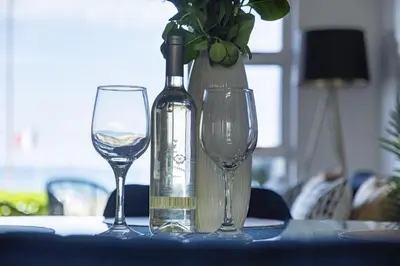 a bottle of wine and two glasses on a table at Sea Spray AG04 in Bloubergstrand