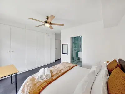 a white bedroom with a bed and a ceiling fan at Pool, Gym, self check-in,Parking in Cape Town