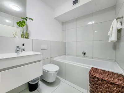 a white bathroom with a tub and a toilet and a sink at Pool, Gym, self check-in,Parking in Cape Town