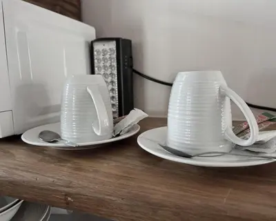 two white cups and saucers sitting on a counter at Kabana Family Home and Guest House in Cape Town