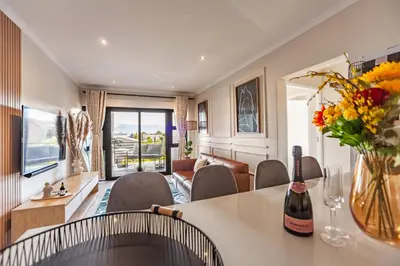 a living room with a table and chairs at Chic Modern 2 bedroom beachfront with views, 6 Blue Tides in Bloubergstrand