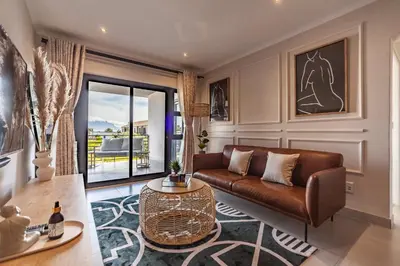 a living room with a couch and a table at Chic Modern 2 bedroom beachfront with views, 6 Blue Tides in Bloubergstrand