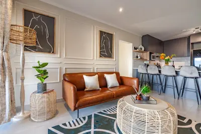 a living room with a couch and a table at Chic Modern 2 bedroom beachfront with views, 6 Blue Tides in Bloubergstrand