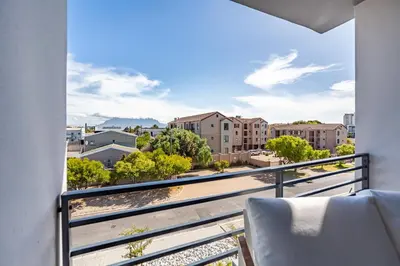 a balcony with a view of a city at Chic Modern 2 bedroom beachfront with views, 6 Blue Tides in Bloubergstrand