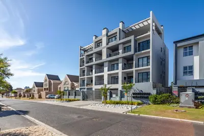 a white apartment building on a street with houses at Chic Modern 2 bedroom beachfront with views, 6 Blue Tides in Bloubergstrand