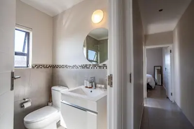 a bathroom with a toilet and a sink and a mirror at Chic Modern 2 bedroom beachfront with views, 6 Blue Tides in Bloubergstrand