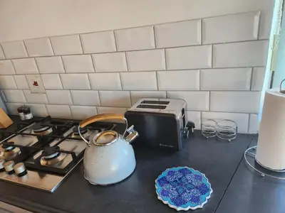 a kitchen counter with a toaster and a tea pot on a stove at Thys' Place in Cape Town