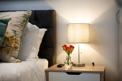 a vase of flowers on a table next to a bed at 505 La Roche, Paarl in Paarl