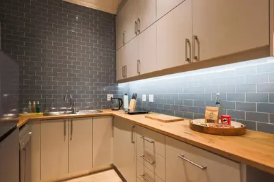 a kitchen with white cabinets and blue tiles on the wall at 505 La Roche, Paarl in Paarl