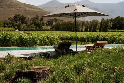 an umbrella and two chairs next to a pool at MAISON FRANSCHHOEK in Franschhoek