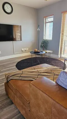 a living room with a couch and a clock on the wall at SS Luxury Apartments in Cape Town
