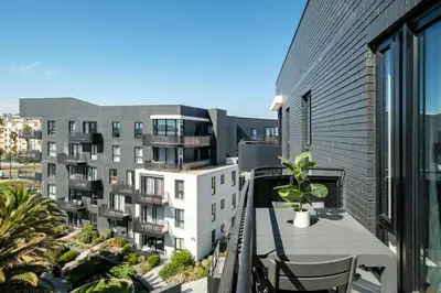 an apartment balcony with a table and a building at Belina - Nine Palms Premier in Cape Town