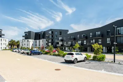 a parking lot with cars parked in front of a building at Belina - Nine Palms Premier in Cape Town