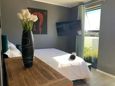 a vase with flowers on a table in a bedroom at Sitari County Estate - The Most Iconic Estate in Cape Town