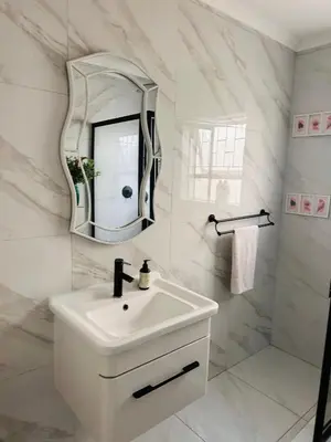 a white bathroom with a sink and a mirror at Entertainers delight near the beach & wine routes in Cape Town
