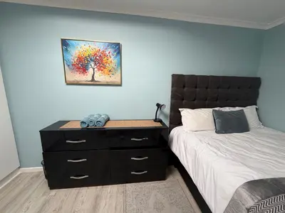 a bedroom with a bed and a dresser with a painting at Entertainers delight near the beach & wine routes in Cape Town