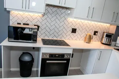 a kitchen with white cabinets and a counter with a microwave at B&B Sitari County Estate - The Most Iconic Estate in Cape Town