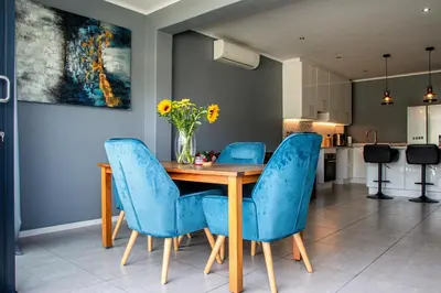 a dining room table with blue chairs and a vase of flowers at B&B Sitari County Estate - The Most Iconic Estate in Cape Town