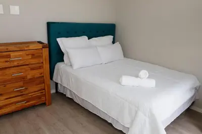a bed with a blue headboard next to a wooden dresser at B&B Sitari County Estate - The Most Iconic Estate in Cape Town