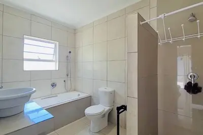 a bathroom with a toilet and a tub and a sink at West Coast comfortable stays in Cape Town