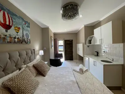 a living room with a bed and a kitchen at DOMIN LUXURY SUITES in Cape Town