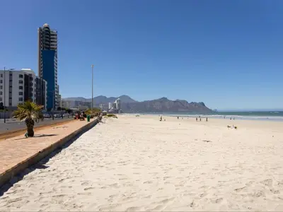 a beach with a long line of people on it at St Tropez Beachfront 101 in Strand