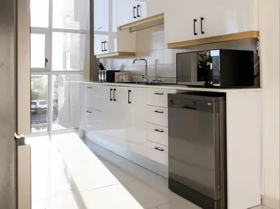 a kitchen with white cabinets and a black dishwasher at St Tropez Beachfront 101 in Strand