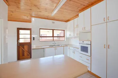 a kitchen with white cabinets and a wooden ceiling at 37 Toner Street North in Cape Town