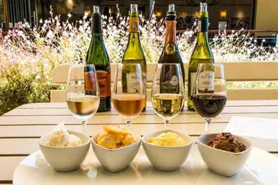 a table with glasses of wine and bowls of food at Spray Villa Bloubergstrand with hot tub and close to the beach in Bloubergstrand