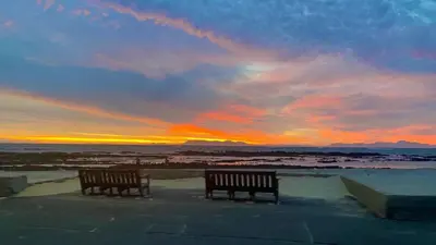 two benches in front of the ocean at sunset at Ocean Escape in Strand