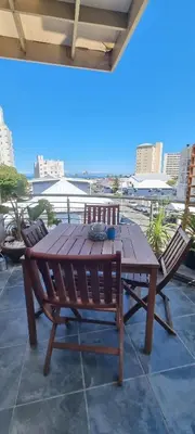a wooden table and chairs with a view of the city at Ocean Escape in Strand