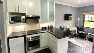 a kitchen with white cabinets and a microwave at Studio 23 @ Huis Piron. The Heart of Stellenbosch. in Stellenbosch