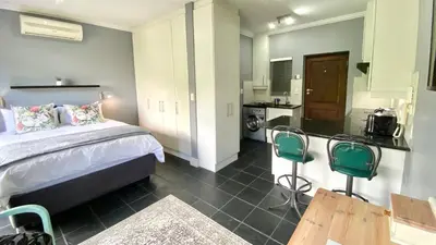 a bedroom with a bed and a kitchen with a counter at Studio 23 @ Huis Piron. The Heart of Stellenbosch. in Stellenbosch