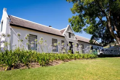 a white building with flowers in front of it at Laborie Jonkershuis in Paarl