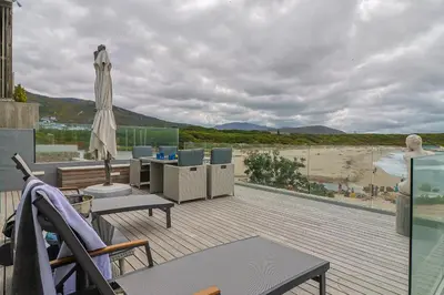 a balcony with an umbrella and a view of a beach at 91 Atlantic Drive in Hermanus