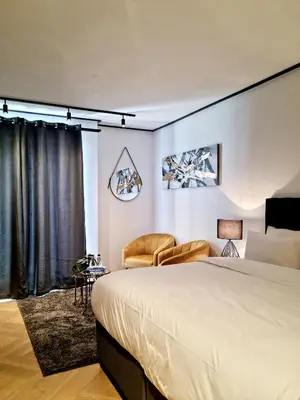 a bedroom with a large bed and a chair at 9 Palms by Smart City Stays in Cape Town