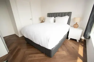 a bedroom with a large white bed and wooden floors at 9 Palms by Smart City Stays in Cape Town