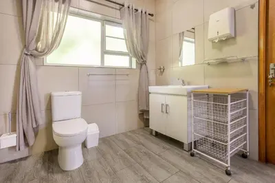 a bathroom with a toilet and a sink and a window at 55 MainStay in Hermanus