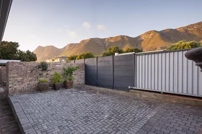 a fence with mountains in the background with a patio at 55 MainStay in Hermanus
