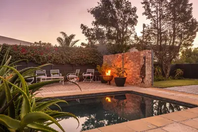 a backyard with a pool with chairs and a fire pit at 55 MainStay in Hermanus