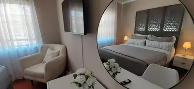 a mirror reflecting a bedroom with a bed and a chair at Blouberg Beach Villa in Cape Town