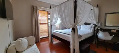 a bedroom with a canopy bed and a chair at Blouberg Beach Villa in Cape Town