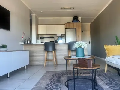 a living room with a table and chairs and a kitchen at The CoziPlace One in Cape Town